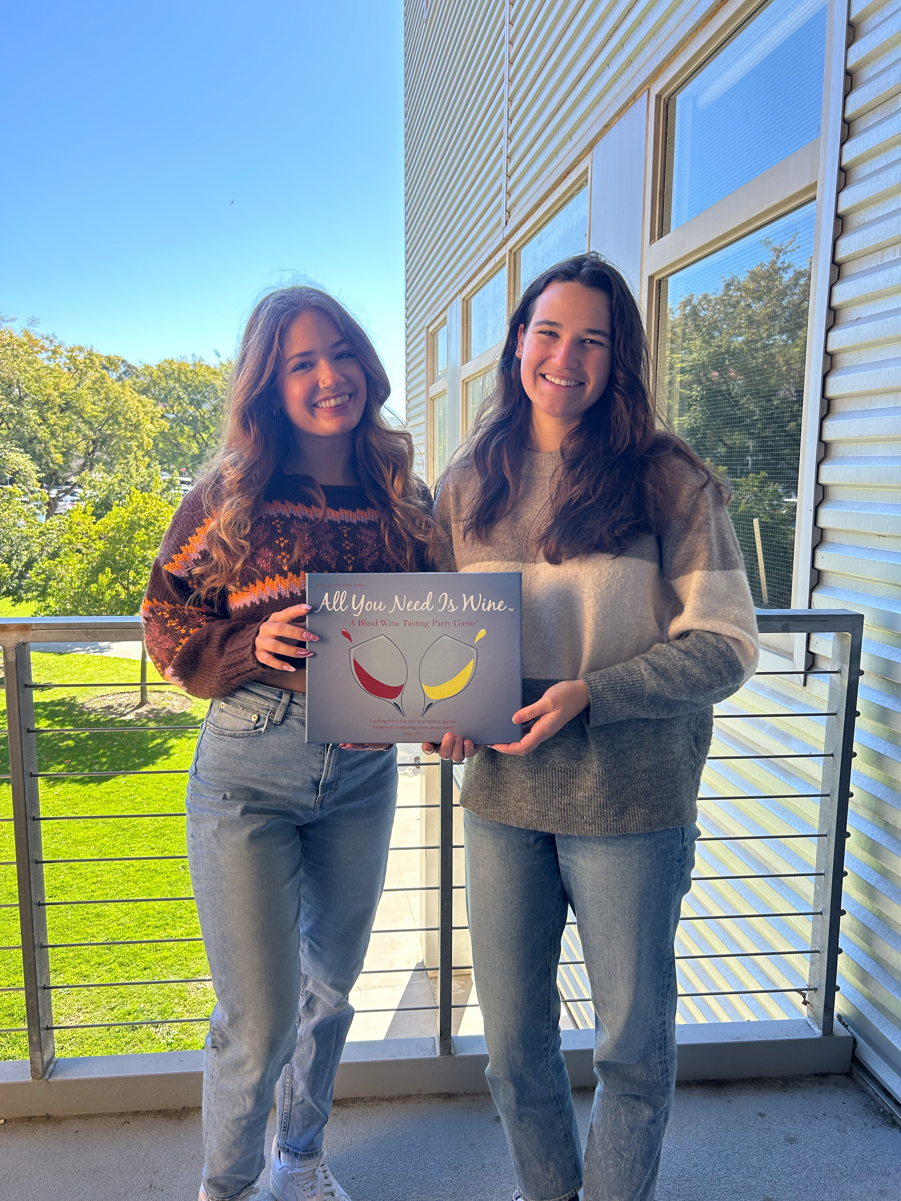 Engineering management students Darla Doell and Madison Pierce show off the party game All You Need is Wine, created by Cal Poly alumni Carlene and Daniel Iverson.