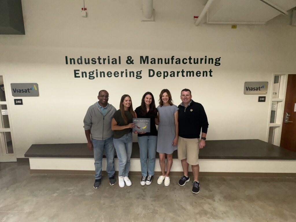 Five people standing in front of a large wall decal that reads Industrial & Manufacturing Engineering Department.